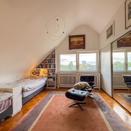 Helles Dachgeschoss-Schlafzimmer mit großem Fenster und Stadtblick über Krefeld.
