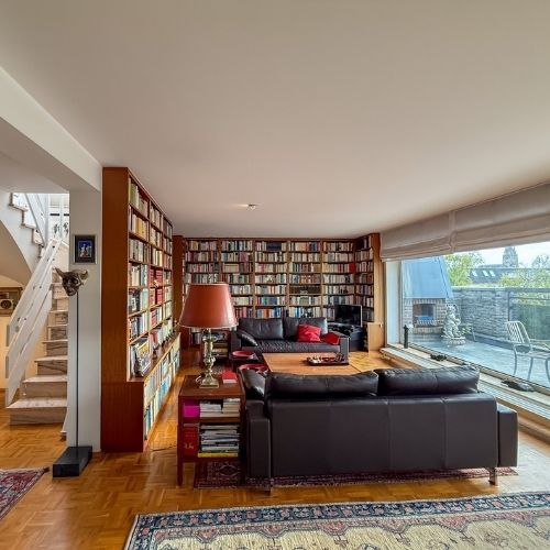 Großzügiges, lichtdurchflutetes Wohnzimmer mit Bibliothek und Zugang zum Balkon in einer modernen Maisonette-Eigentumswohnung in Krefeld.